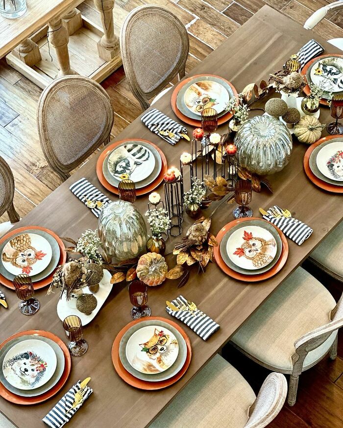 Thanksgiving table decor with owl-themed plates, pumpkins, striped napkins, and autumn accents for a cozy celebration.