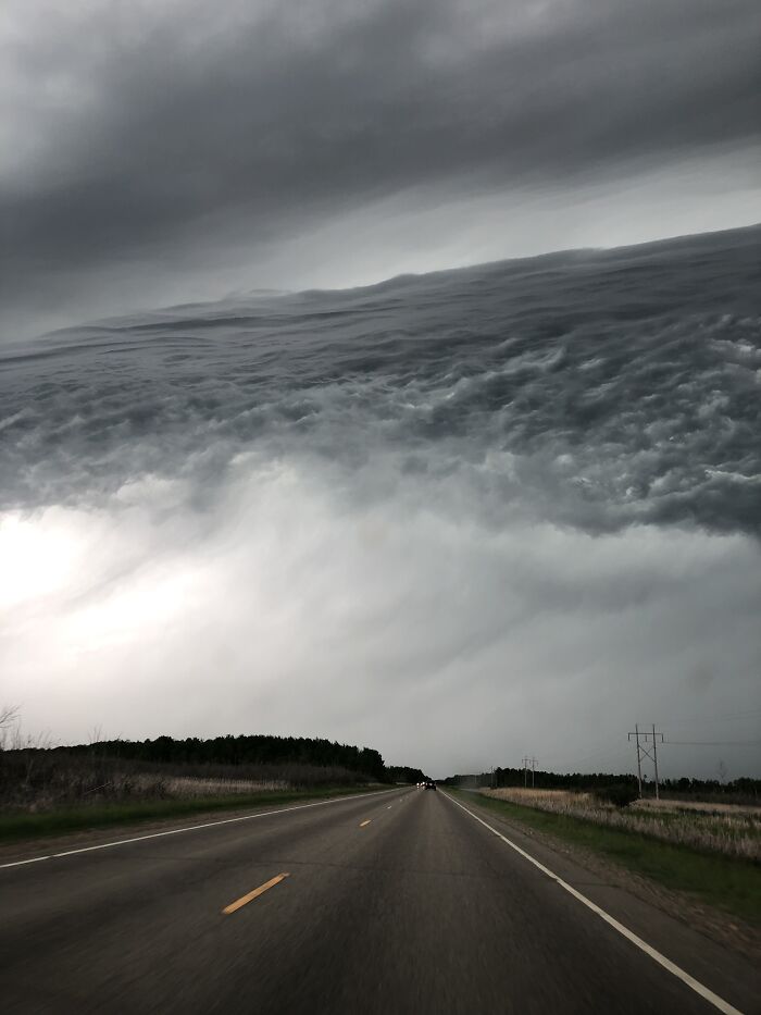 Road leading to horizon under fascinating cloud shapes in dramatic sky.