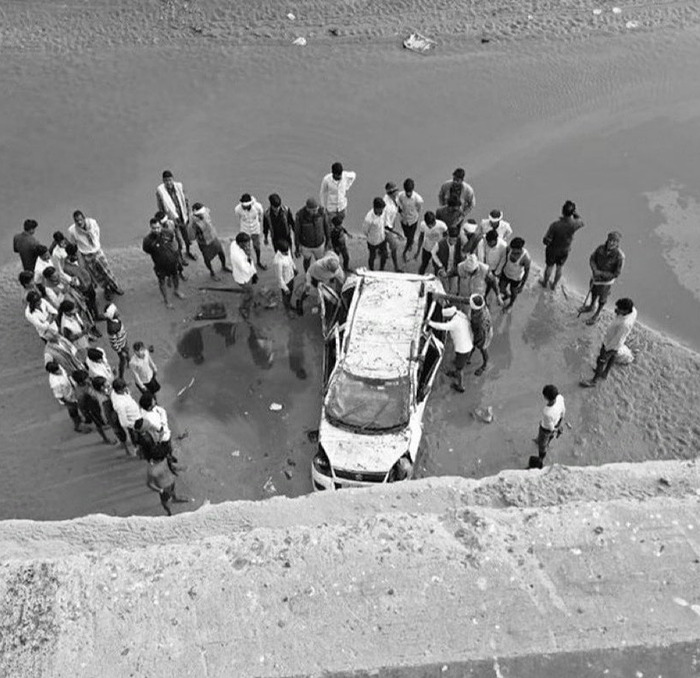 Crowd gathers around a car after a fatal crash, sparking concerns over Google Maps guidance on unfinished bridge. Crowd gathers around a car after a fatal crash, sparking concerns over Google Maps guidance on unfinished bridge.