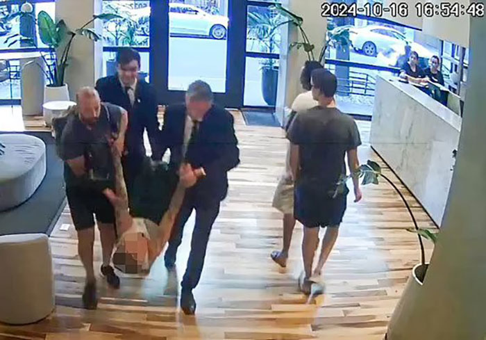 Security footage showing a group of people carrying someone in a hotel lobby. Security footage showing a group of people carrying someone in a hotel lobby.