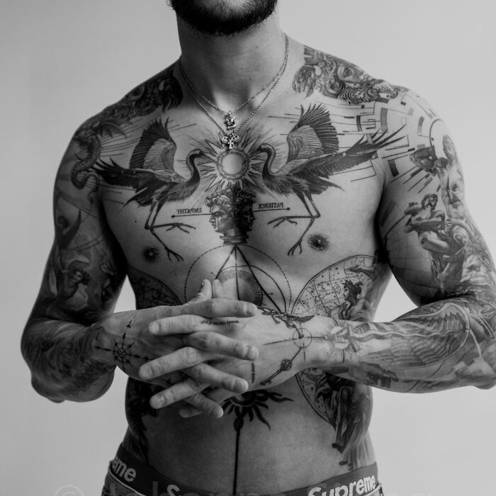 Monolith Studio artist showcases intricate chest and arm tattoos in black and white.