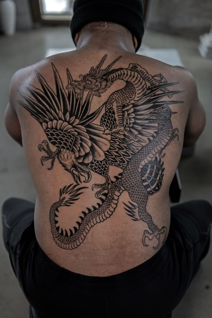Back tattoo of a dragon by Monolith Studio artist, showcasing intricate details and bold design.