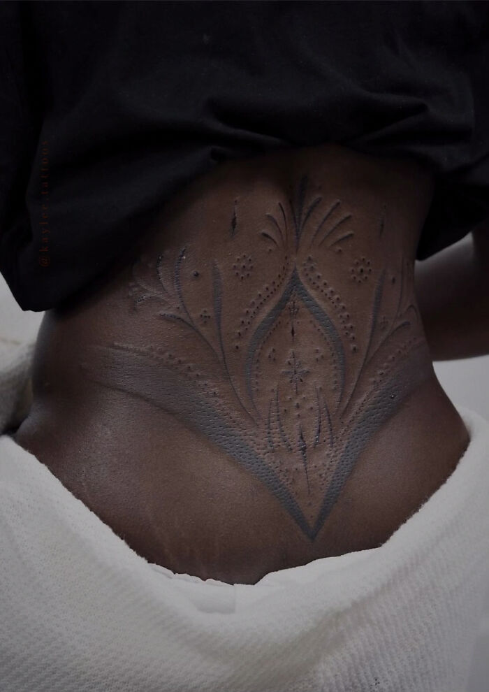 Intricate tattoo design by Monolith Studio artist on a person's lower back, featuring delicate patterns and lines.