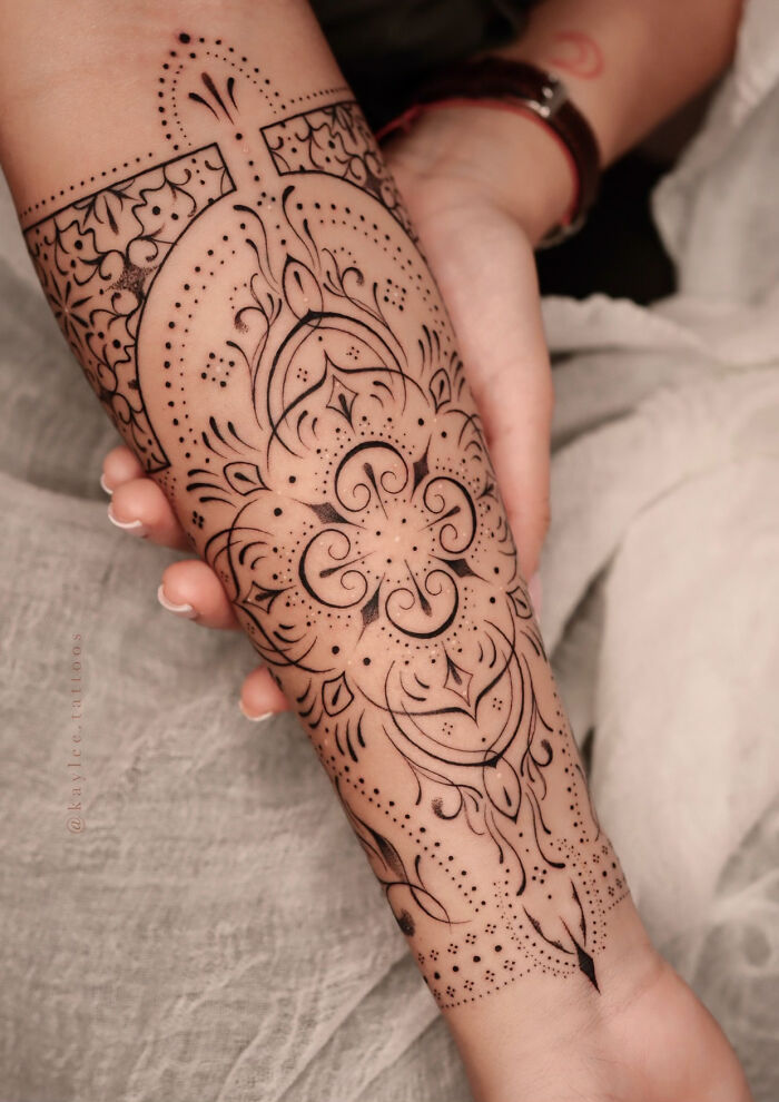 Intricate tattoo on forearm by Monolith Studio artist, featuring floral and geometric patterns.