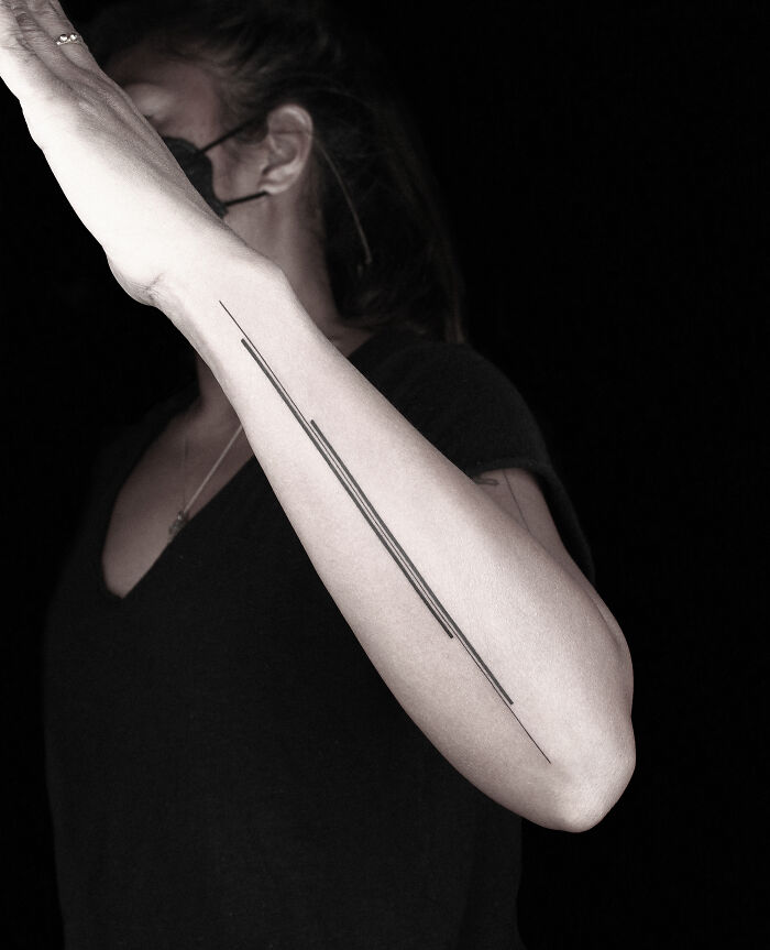 Arm tattoo with minimalist black lines by Monolith Studio artist.