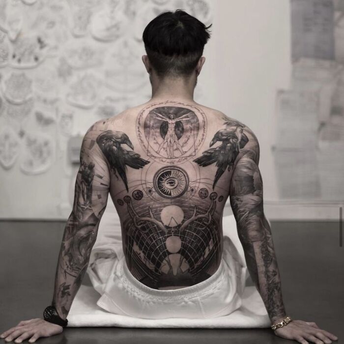 Back view of a person with intricate tattoos by Monolith Studio artists, featuring geometric and mythological designs.