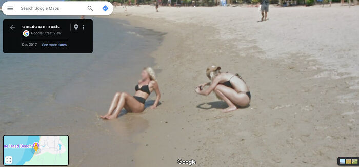 Two women on a beach, one taking a photo of the other, captured on Google Street View.