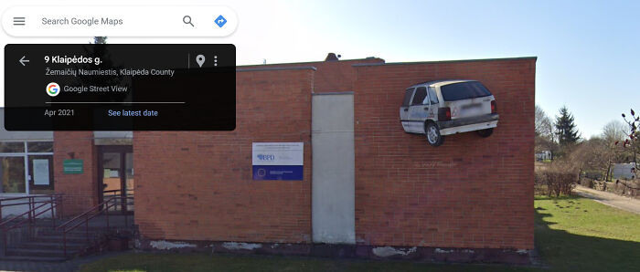 Car embedded in a brick wall, captured on Google Street View, showcasing a funny and weird life scene.