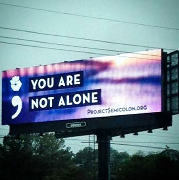 A billboard with a semicolon symbol and the message 
