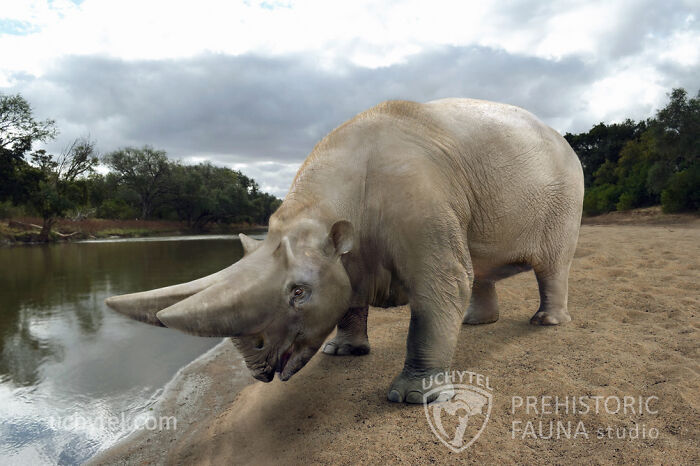 Paleoartist depiction of prehistoric fauna, featuring an ancient creature by a riverbank under a cloudy sky.