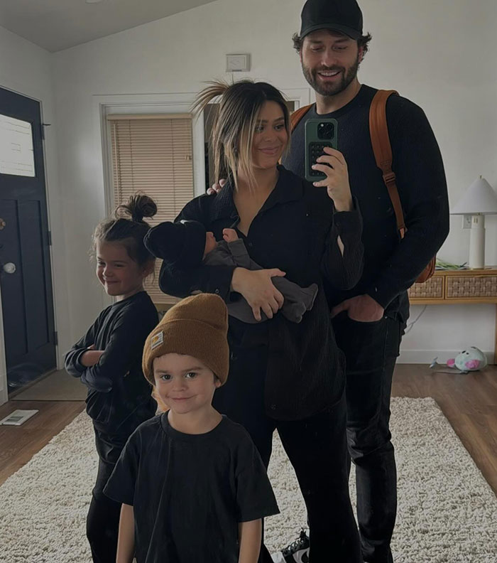 Family taking a mirror selfie in a living room, unrelated to Mormon soft-swinging parties footage or MomTok scandal.