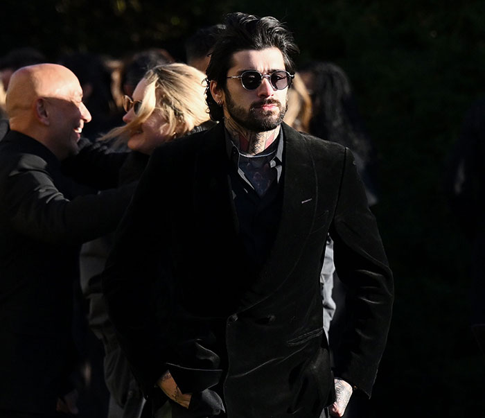 Man in a dark suit and sunglasses at an outdoor event, surrounded by people. Man in a dark suit and sunglasses at an outdoor event, surrounded by people.