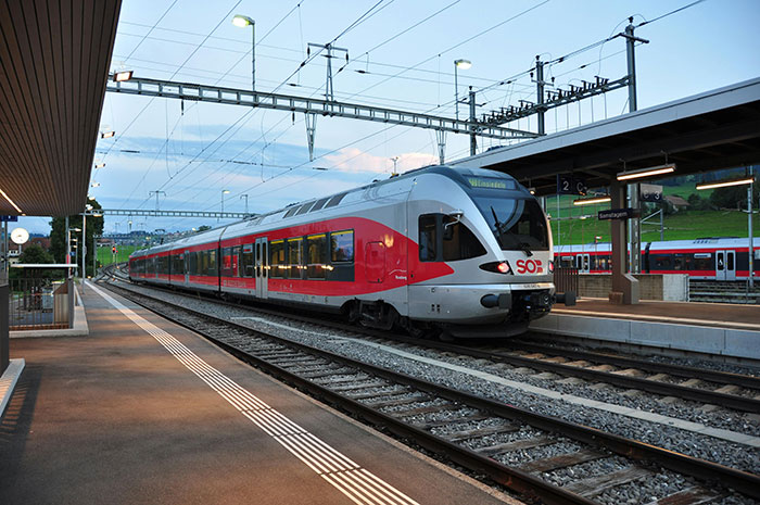 Red and white train at station platform, related to passenger trauma from a scenic route detour. Red and white train at station platform, related to passenger trauma from a scenic route detour.