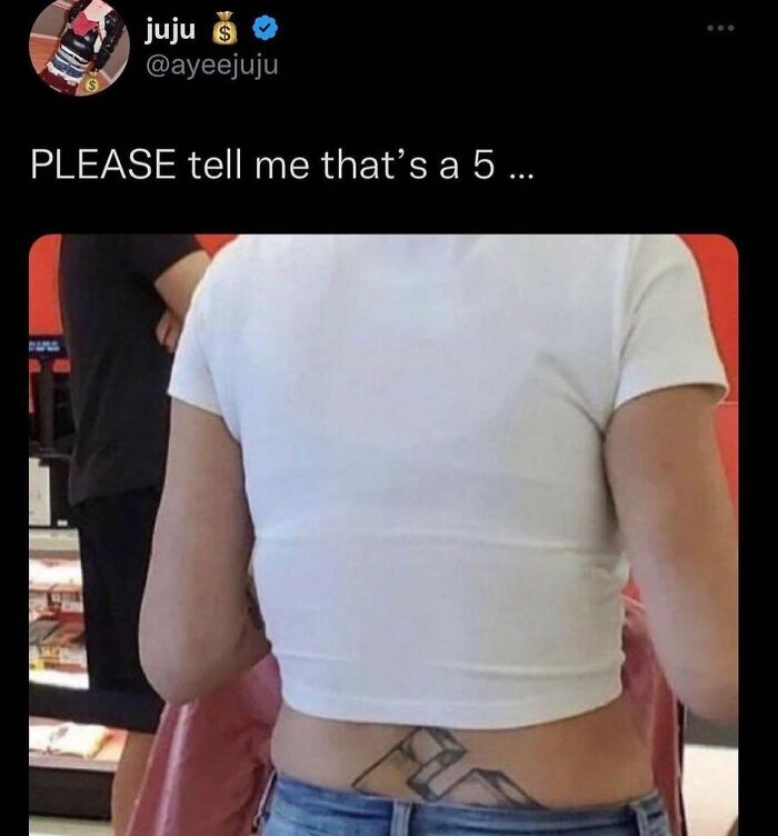 Back tattoo fail with number looking off; person wearing a white crop top in a store.