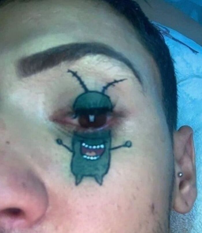 Epic tattoo fail featuring a cartoon bug tattooed around an eye, creating a humorous optical illusion.