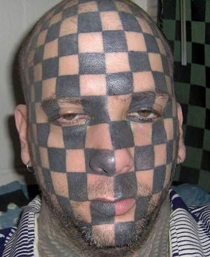 Man with a full-face tattoo of a black checkerboard pattern, illustrating an epic tattoo fail.