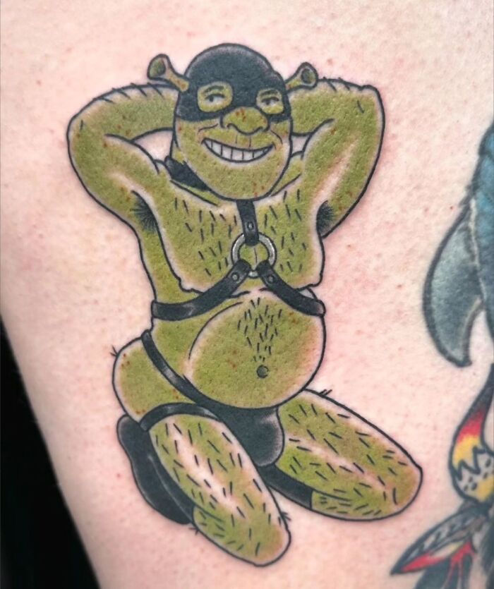 Cartoon character Shrek in unusual attire tattooed on skin, illustrating a humorous tattoo fail.