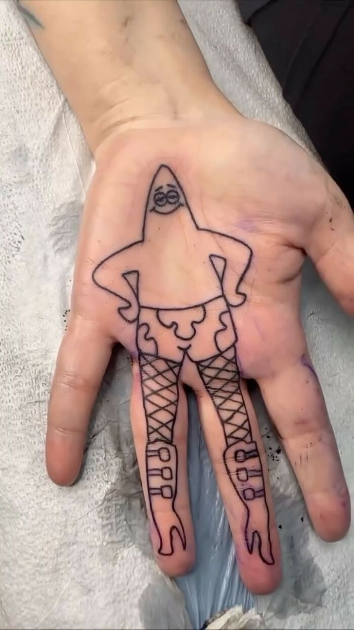 Epic tattoo fail of a cartoon character with funny body and legs inked on a person's palm.