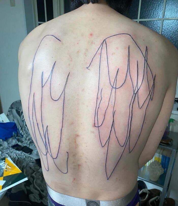 Back tattoo fail with uneven lines resembling wings, highlighting a major tattoo fail shared online for humor.