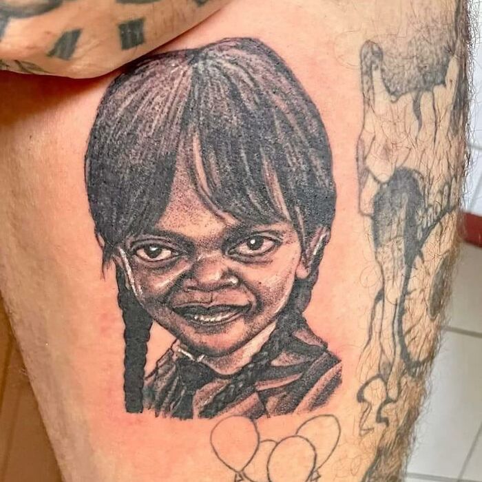 Close-up of an epic tattoo fail featuring an unusual portrait on a person's thigh.