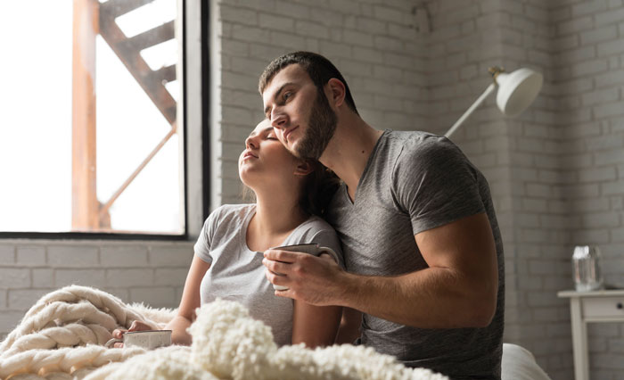 Couple relaxing in bed by a window, sharing a peaceful moment during the day. Couple relaxing in bed by a window, sharing a peaceful moment during the day.
