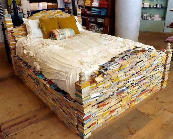 Bed frame made entirely of stacked books, illustrating designers creating pieces without realizing cleaning challenges.
