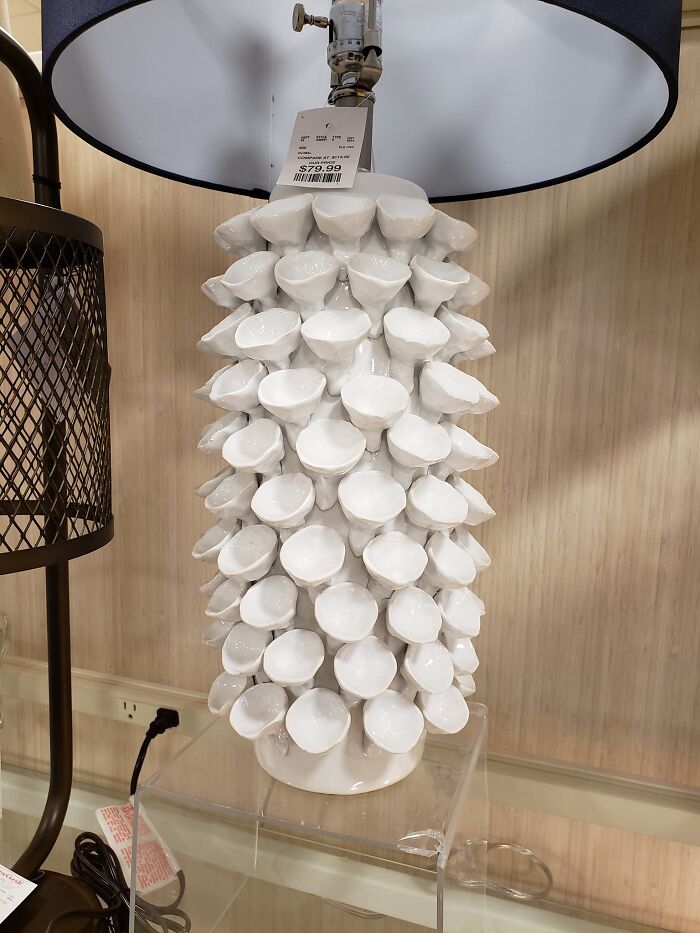 White ceramic lamp base with many small cup-like shapes, showing a design that is difficult to clean for designers.