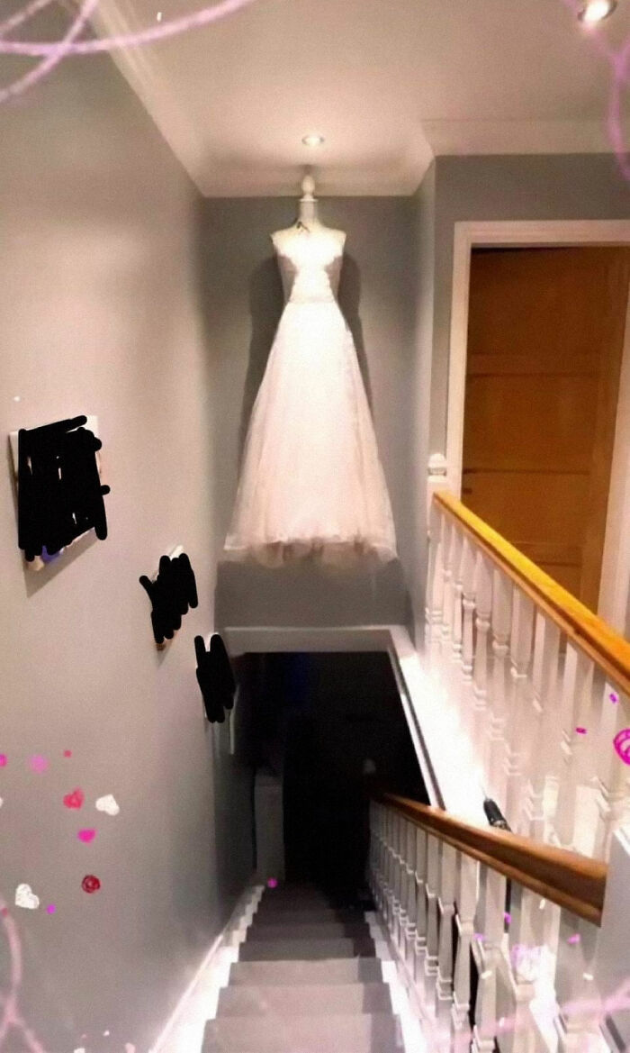 Wedding dress suspended above staircase, a design oversight creating a difficult cleaning challenge for designers.