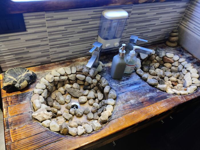 Two stone sinks embedded in a wooden countertop showing a designer creation that will require cleaning challenges.