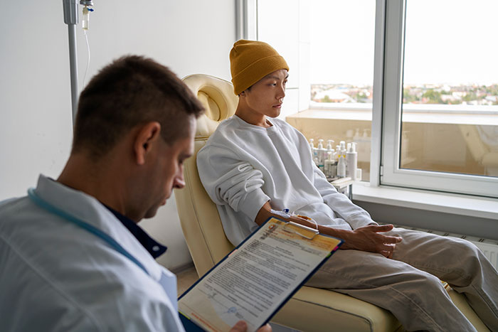 Doctor with clipboard consulting a patient in chemotherapy, focused on the treatment process. Doctor with clipboard consulting a patient in chemotherapy, focused on the treatment process.