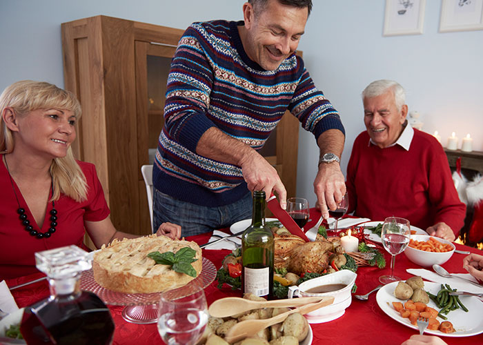 Family gathering at dinner table with festive holiday meal preparation.