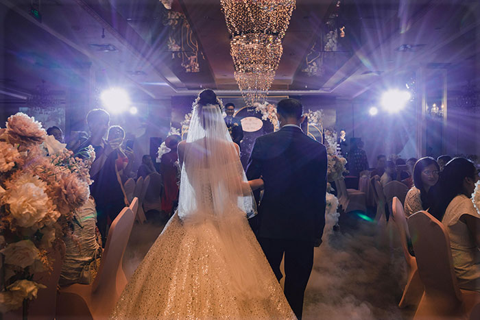 Wedding venue with a bride and groom walking down the aisle, surrounded by guests and floral decorations.