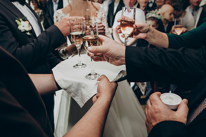 A wedding reception toast with guests raising glasses, celebrating.