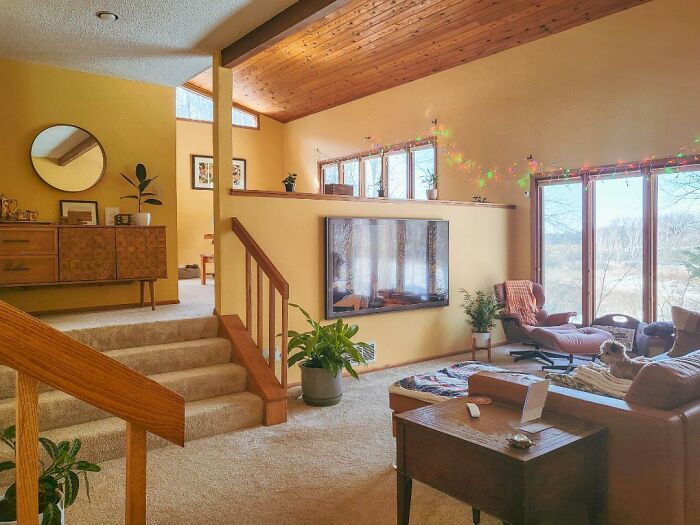 Retro living room with high ceilings, vintage furniture, and large windows, showcasing obsolete luxury home features.