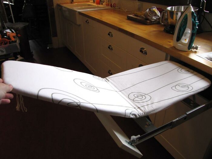 Built-in ironing board in a vintage kitchen, once a luxury home feature, now considered obsolete.