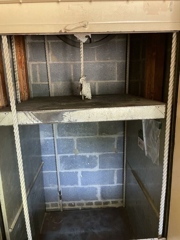 Obsolete home feature: an old-fashioned dumbwaiter with ropes in a brick-walled shaft.