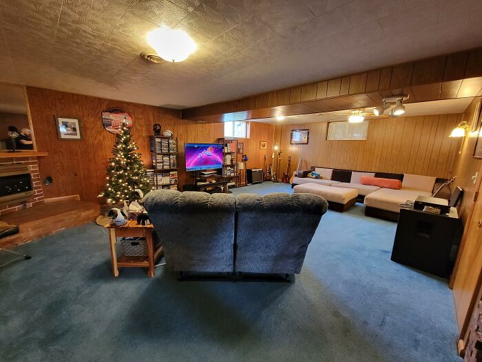 Retro living room with outdated luxury features, blue carpet, wood paneling, and a vintage entertainment center.