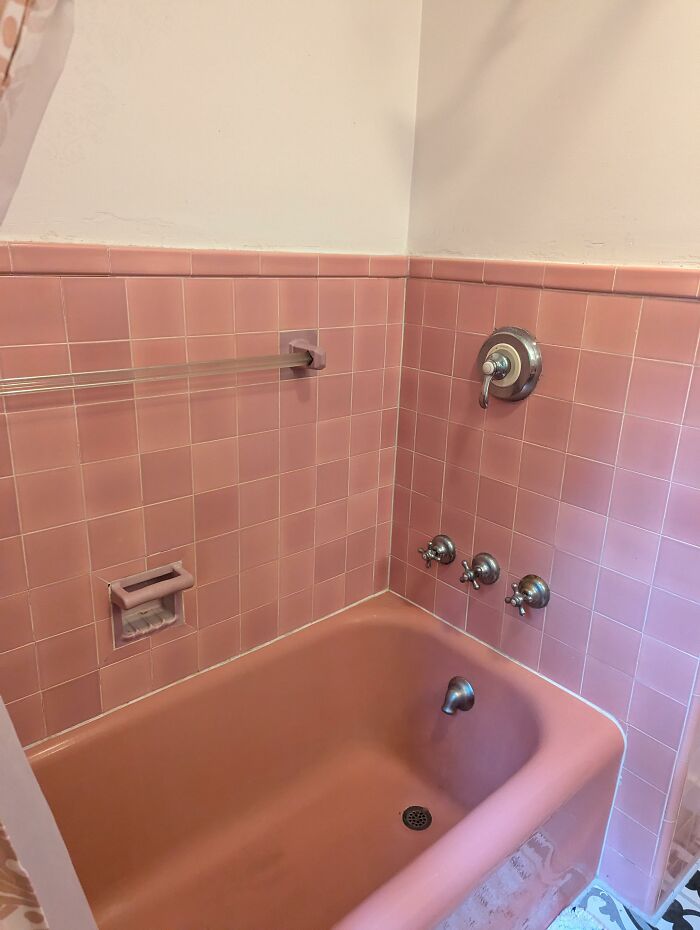 Pink vintage bathtub and tiles, a once luxurious home feature now considered obsolete.