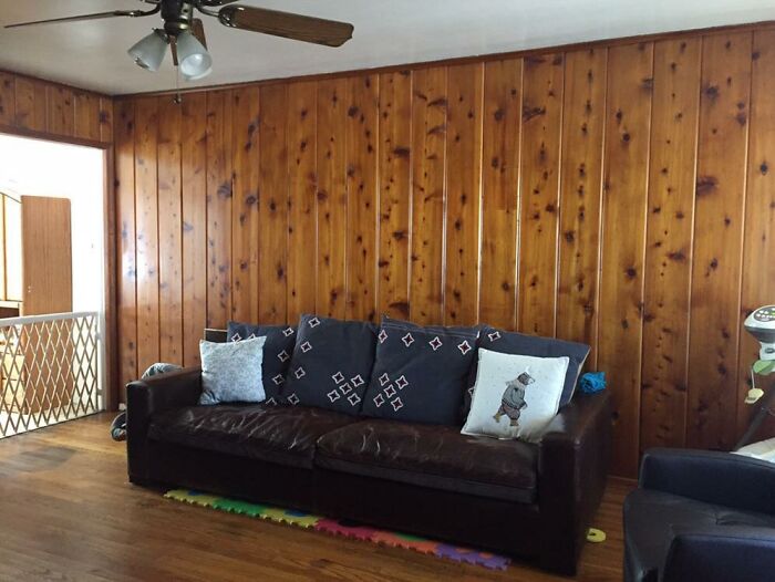 Room with wood paneling and a vintage ceiling fan, showcasing home features that were once luxury but are now obsolete.