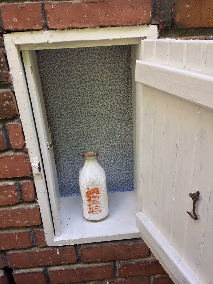 Milk delivery door, an obsolete home feature showcasing past luxury, with a glass bottle in a small cubby.