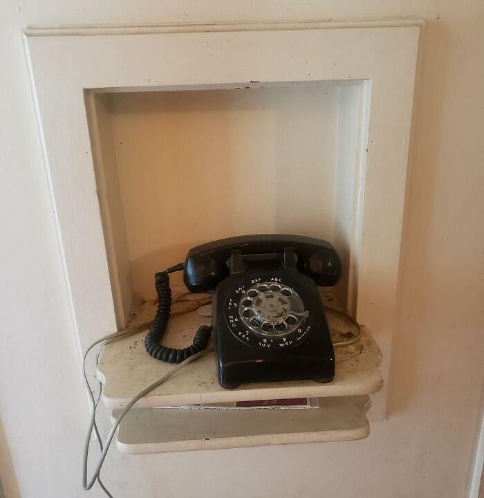 A vintage rotary phone in a wall nook, once a luxury home feature, now obsolete.