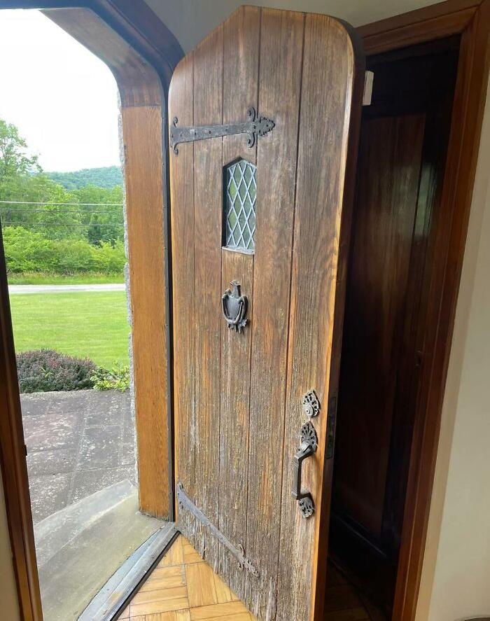 Rustic wooden door with vintage hardware, a once-luxurious home feature now obsolete, opens to a garden view.