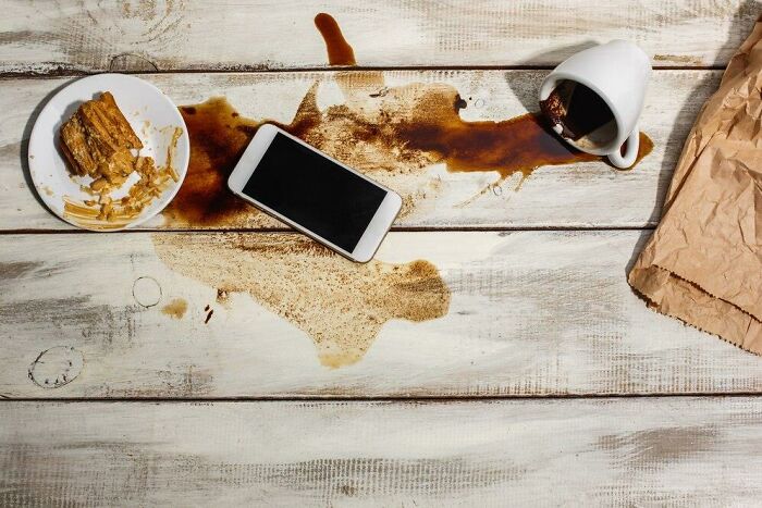 Spilled coffee on a table with a smartphone and plate, illustrating things that make people hate messes.