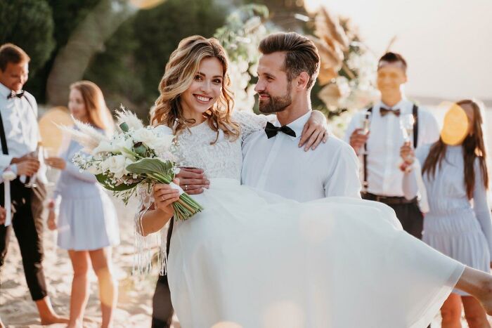 Couple celebrating a wedding on a beach, surrounded by friends, showcasing a risky decision that turned out well.