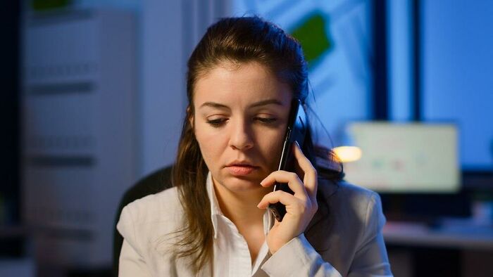 Woman on phone experiencing reverse culture shock, sitting in an office setting.