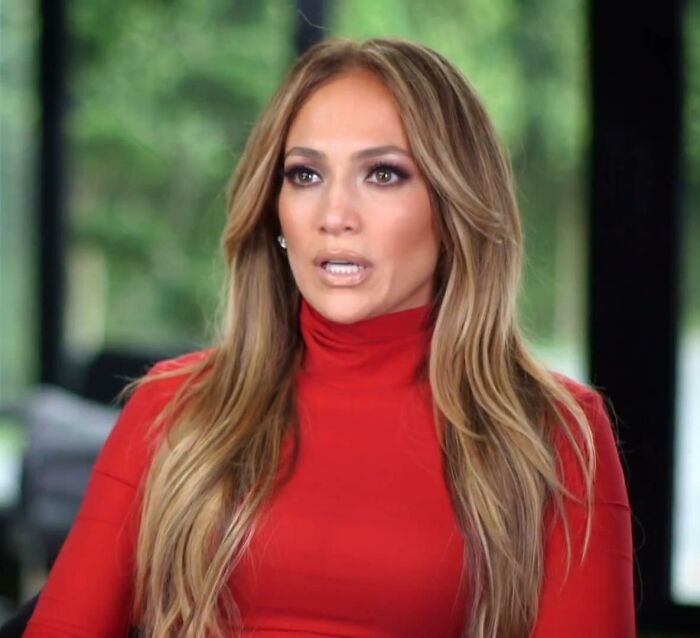 A person in a red turtleneck, sitting indoors, lost in thought, related to celebrities' public image challenges.