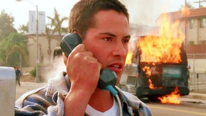 Person talking on phone with a burning vehicle in the background, illustrating a dramatic scene, related to celebrities losing respect.