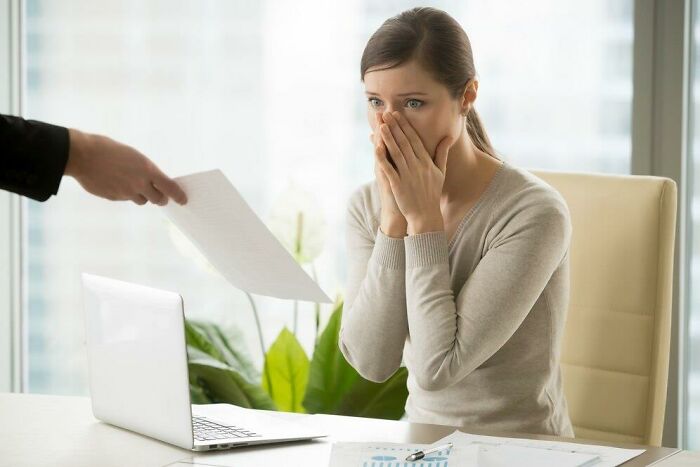 Woman in office shocked by document, highlighting societal double standards.