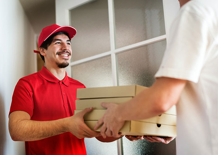 Pizza delivery person handing over boxes, smiling, potential setup for a wild cheating story scenario.