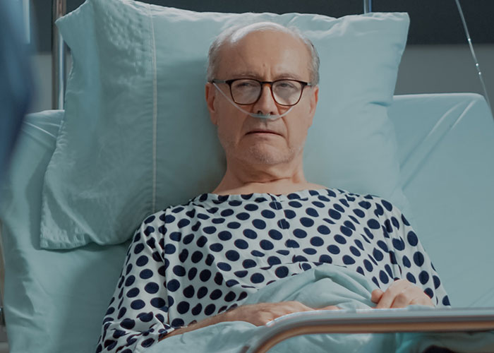 Elderly man in hospital bed wearing polka dot gown, related to wild cheating stories.